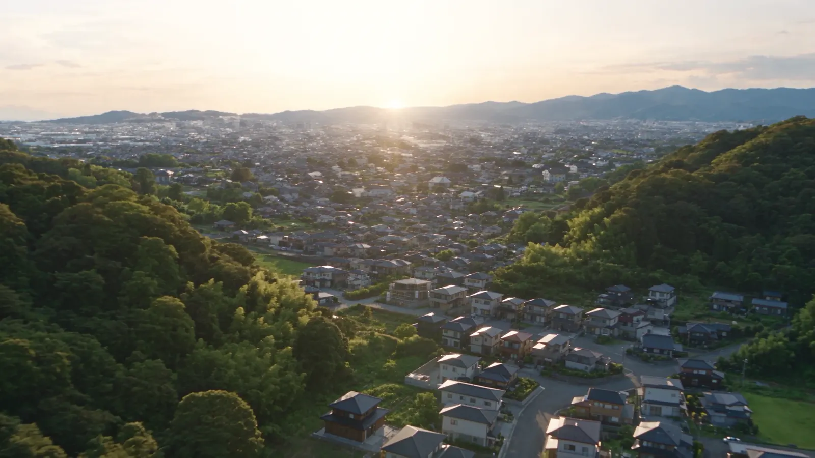 山に囲まれた住宅街を朝日が照らす風景